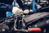 Auto car repair service center. Mechanic checking engine oil level